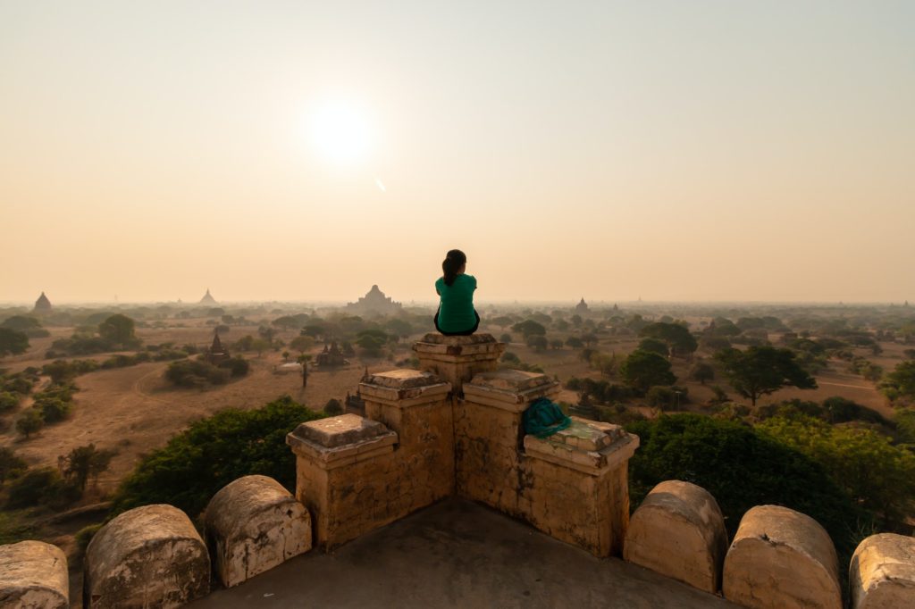 Lone person sits on top of a temple overlooking old Bagan, Myanmar