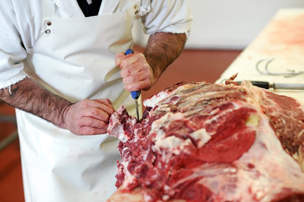 Butcher cutting meat in butcher shop