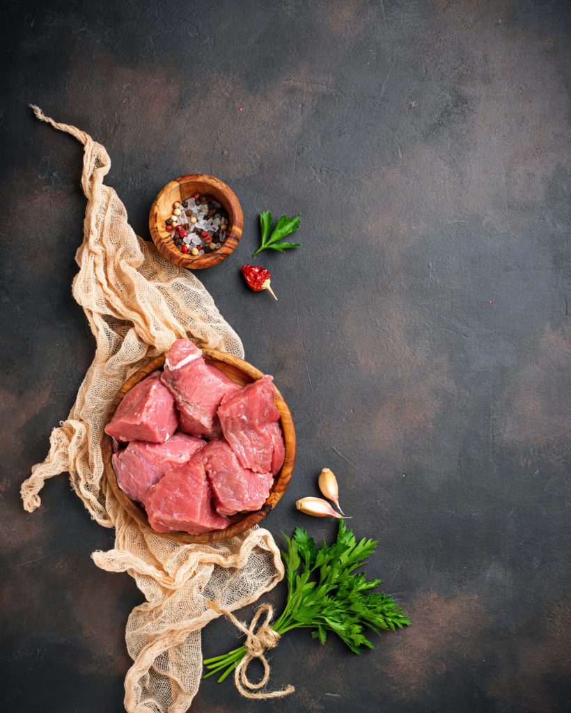 Raw chopped meat with spices on rusty background