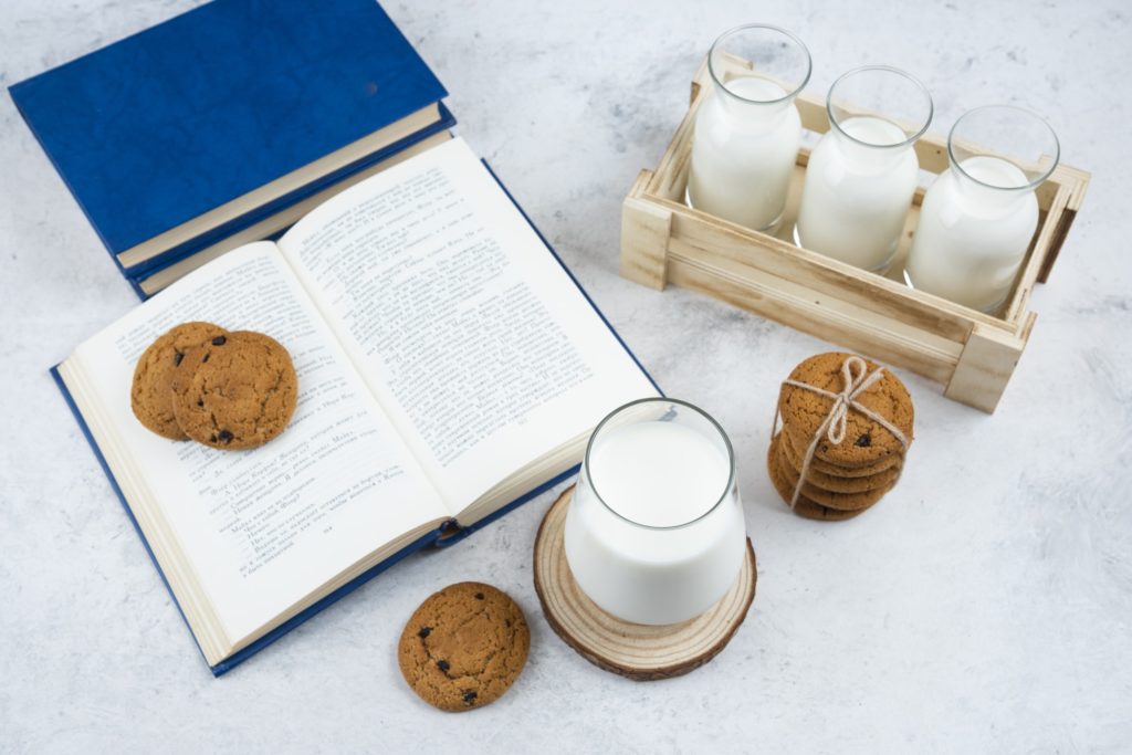 Delicious cookies with glass of milk and book
