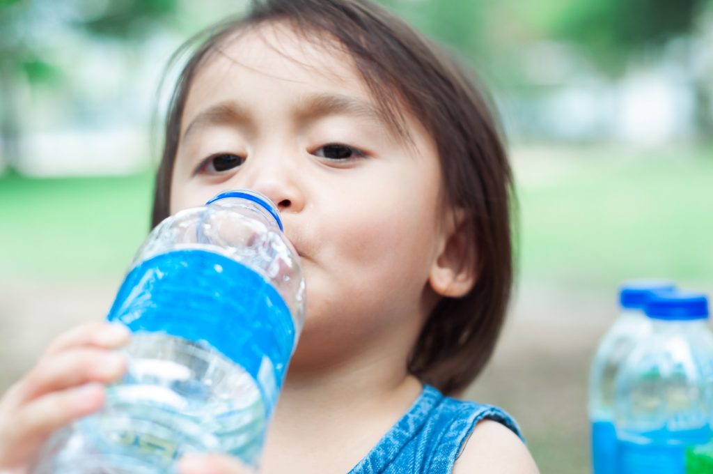 toddler girl drinking water from clear water bottle