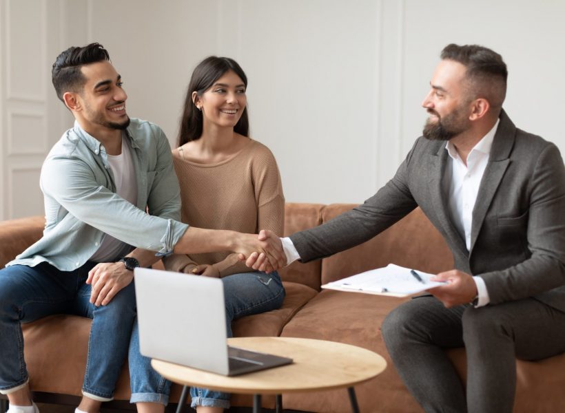 Millennial Couple Buying New Apartment, Shaking Hands With Realtor