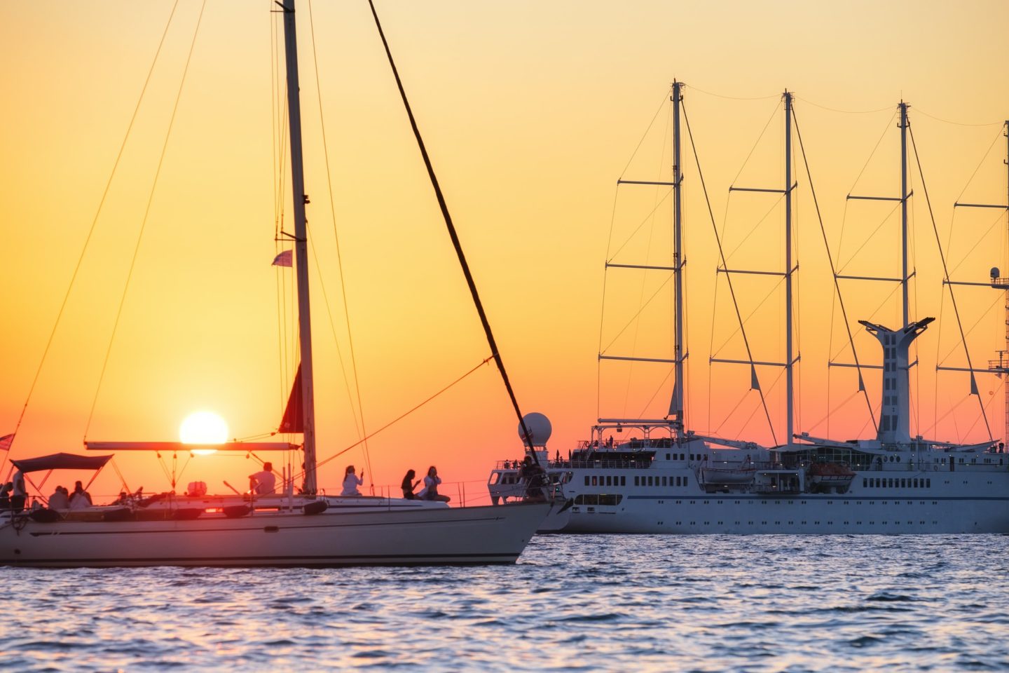 Sailing yachts during sunset. Silhouettes of yachts against the sun.