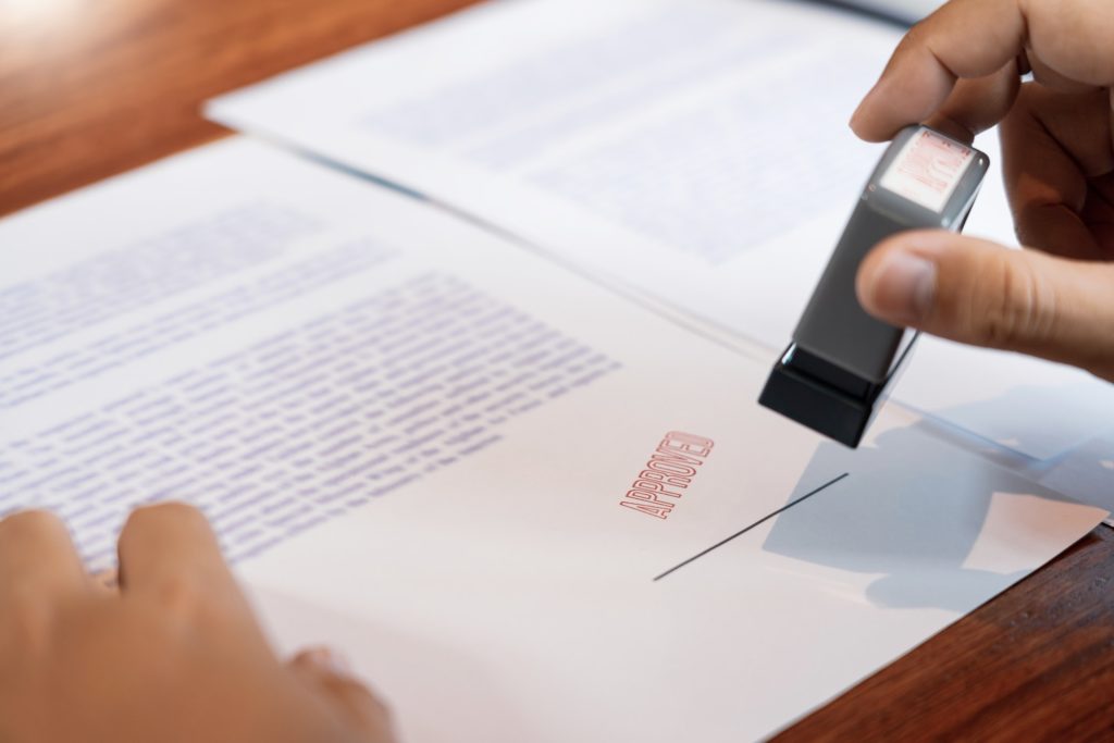 businessman Hand notary public hand ink appoval stamper Stamping seal On Approved Contract Form