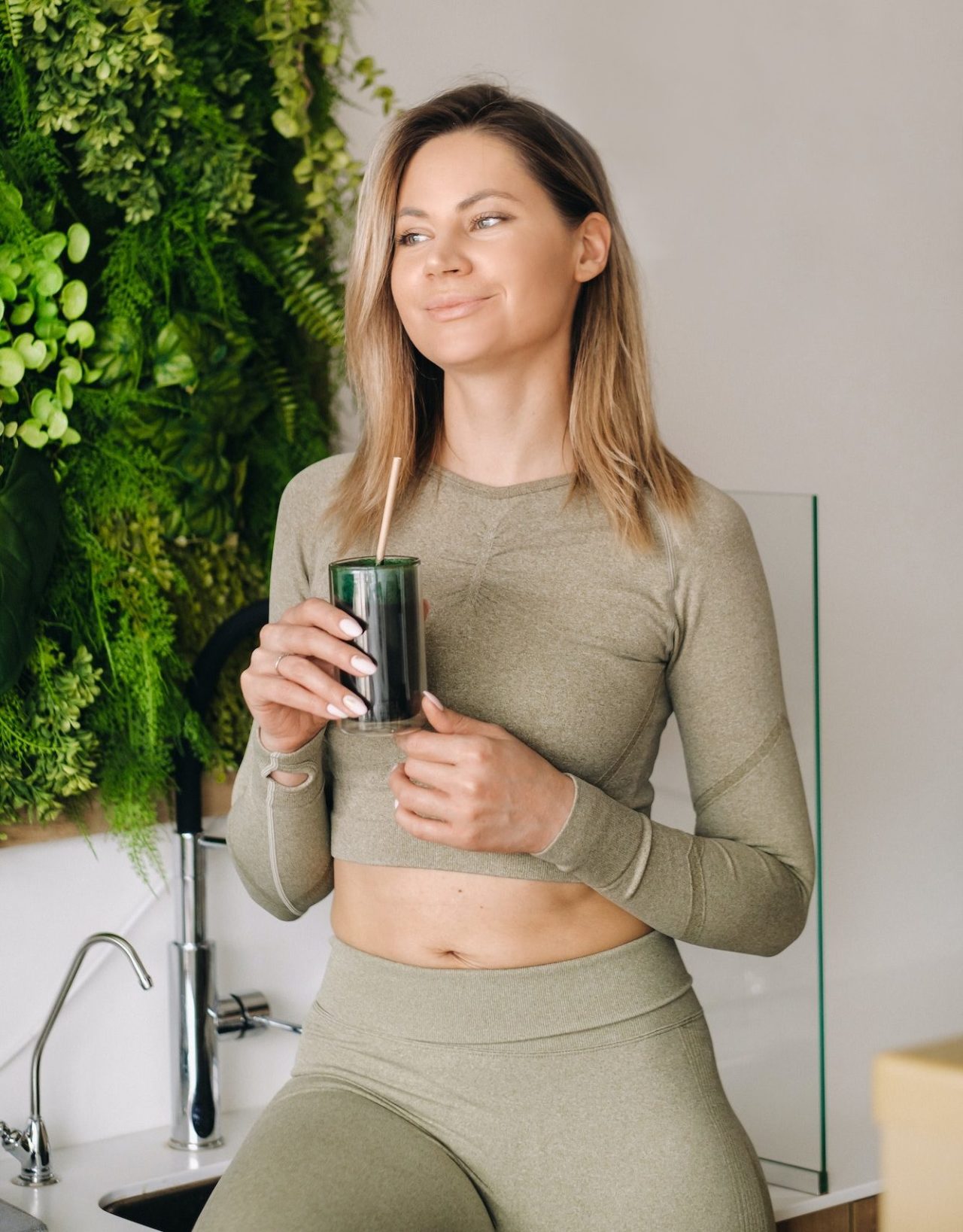 A sporty woman in sportswear holds a smoothie cocktail in her hand. The concept of healthy eating