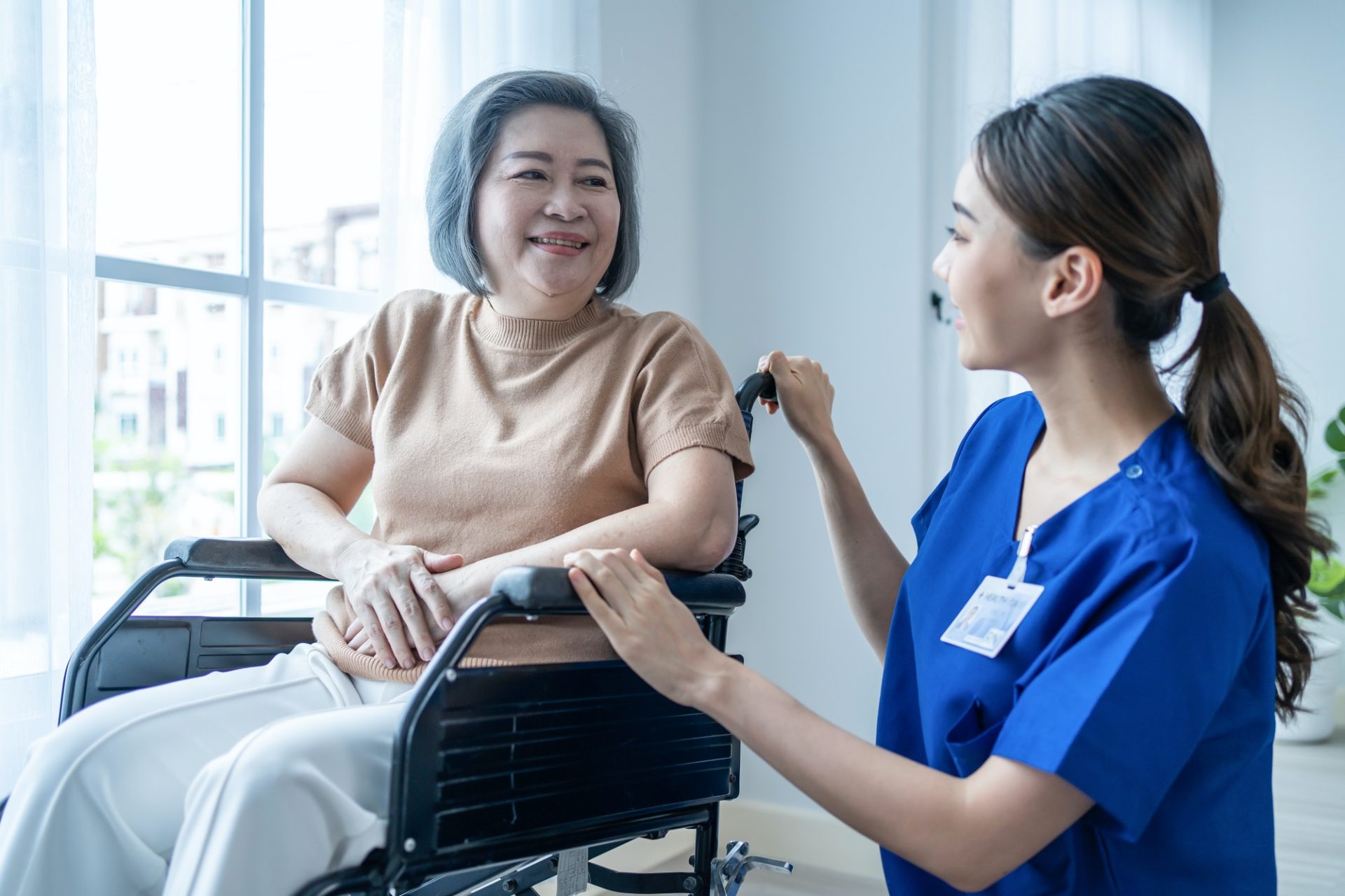 Asian nurse take care senior woman on wheelchair at nursing home care.