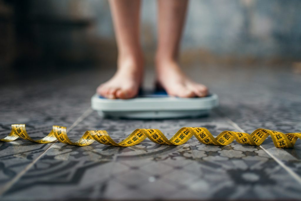 Female feet on the scales, measuring tape