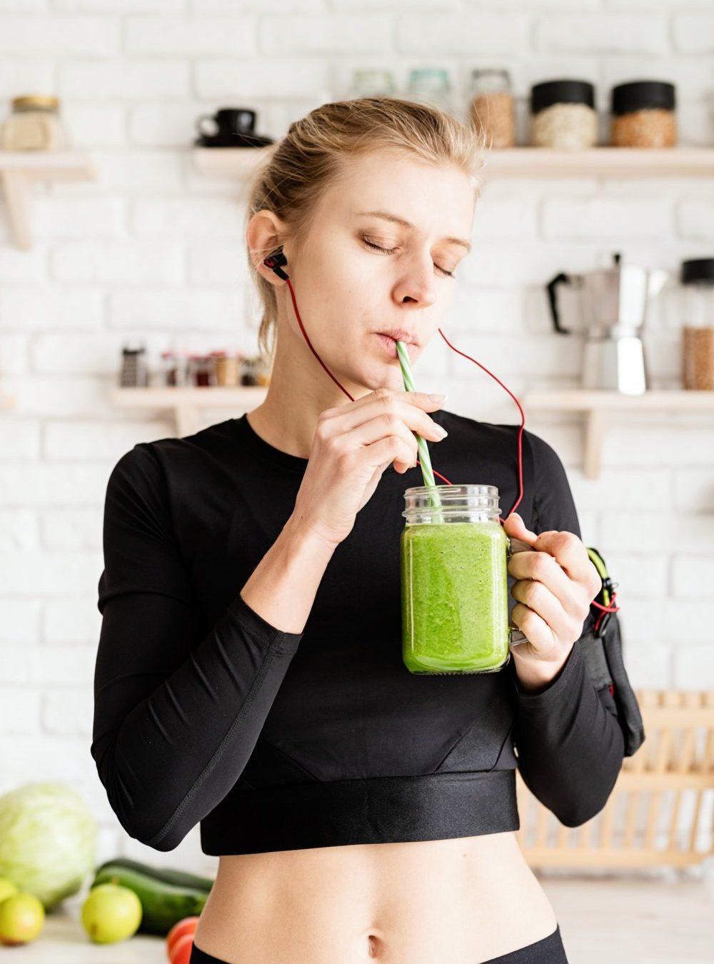 Healthy eating, dieting concept. Young blond woman drinking green smoothie from mason jar at home ki