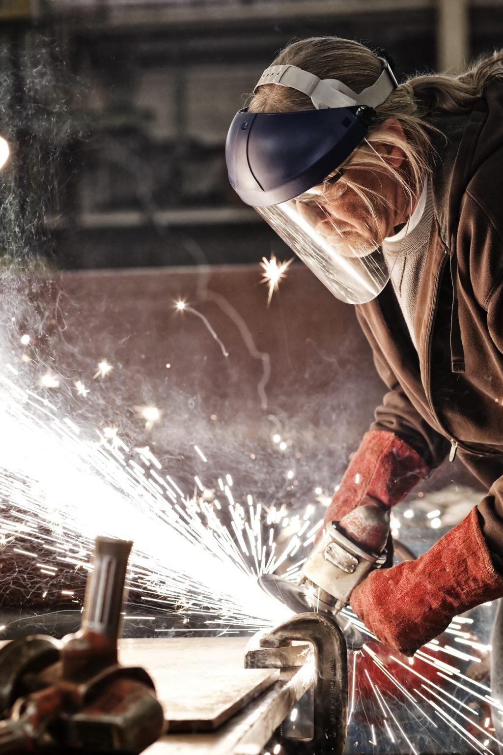 Factory worker grinding a steel edge in a sheet metal factory.