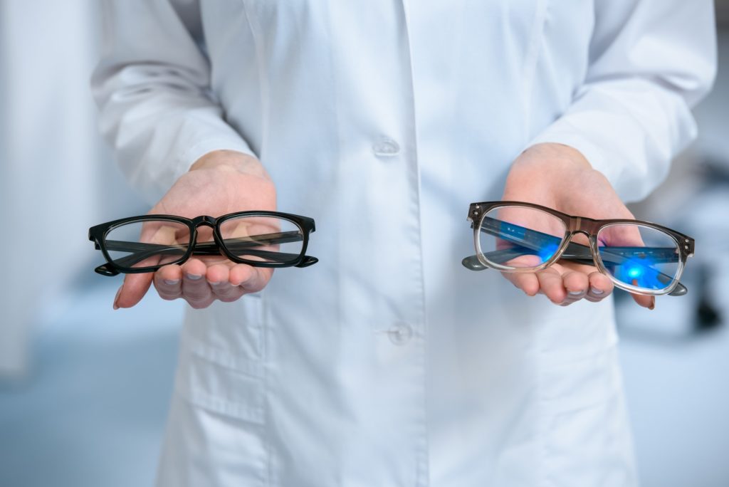 cropped view of optometrist holding different eyeglasses in hands