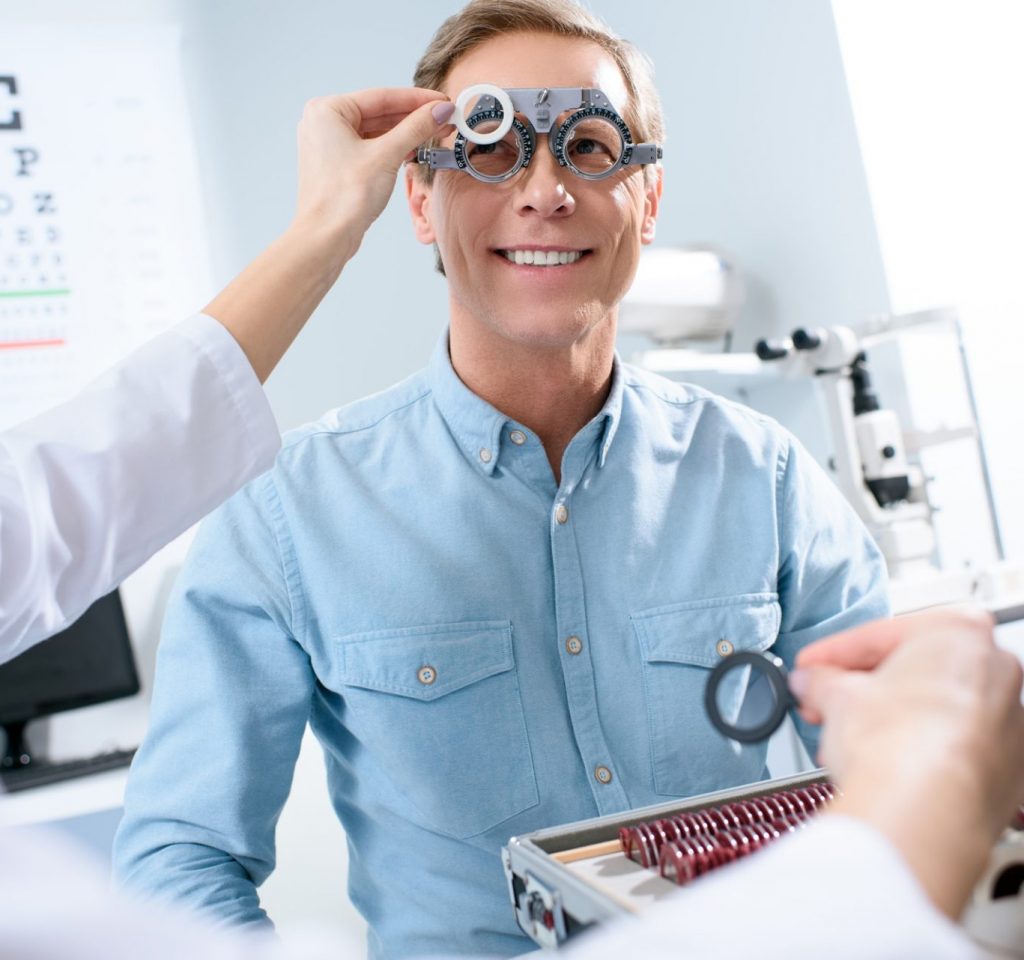 ophthalmologist examining middle aged man eyes with trial frame and lenses