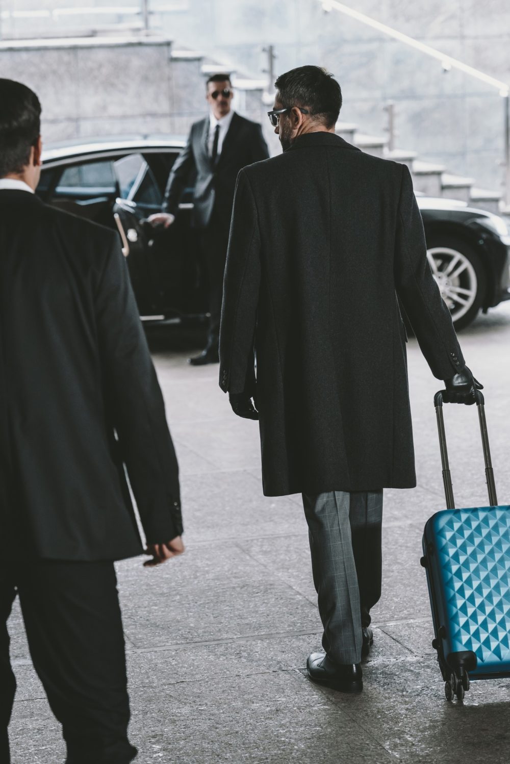 businessman going with blue travel bag to car