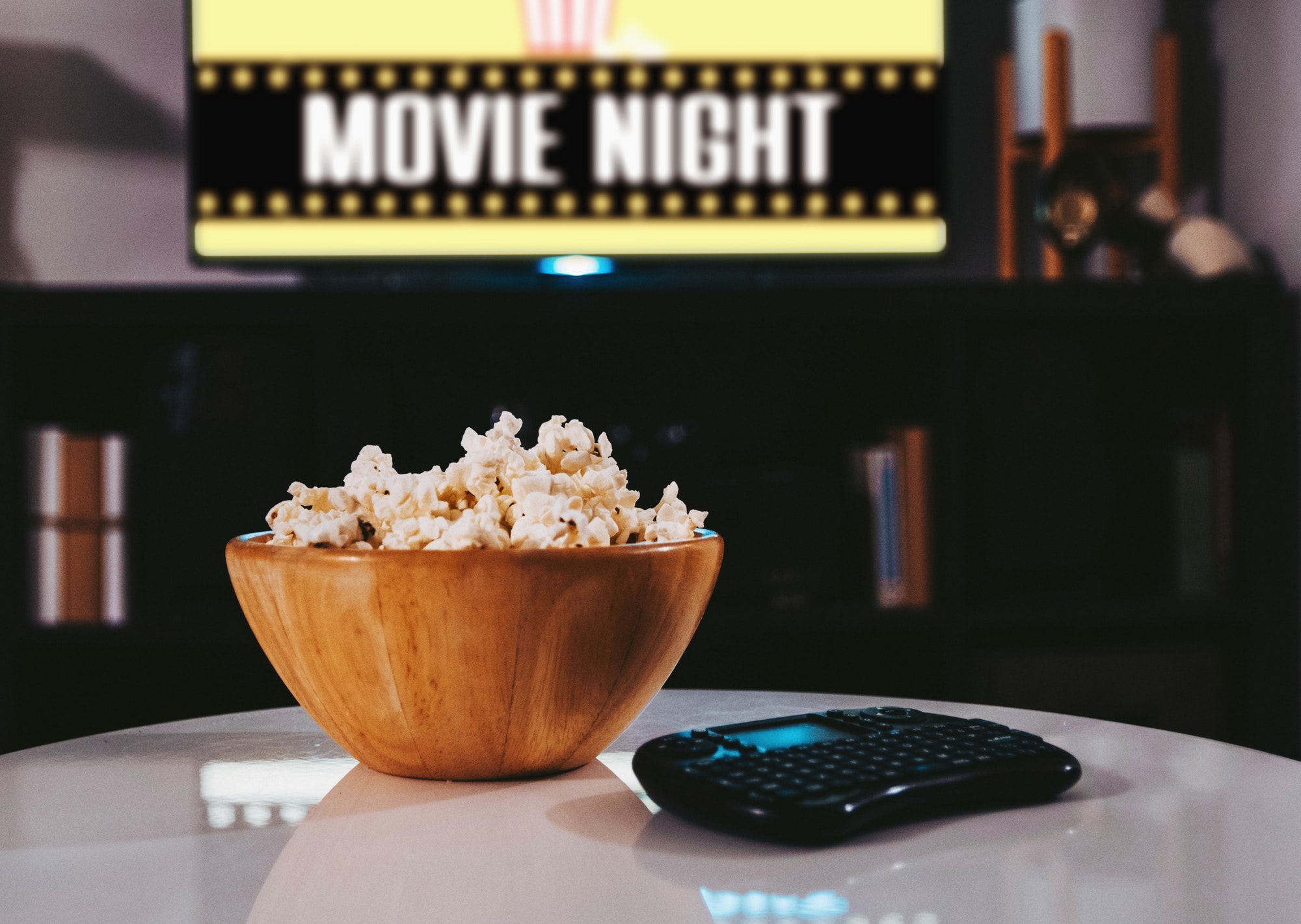 Bowl of popcorn, tv in background, movie night, home, lifestyle, remote, watching tv.