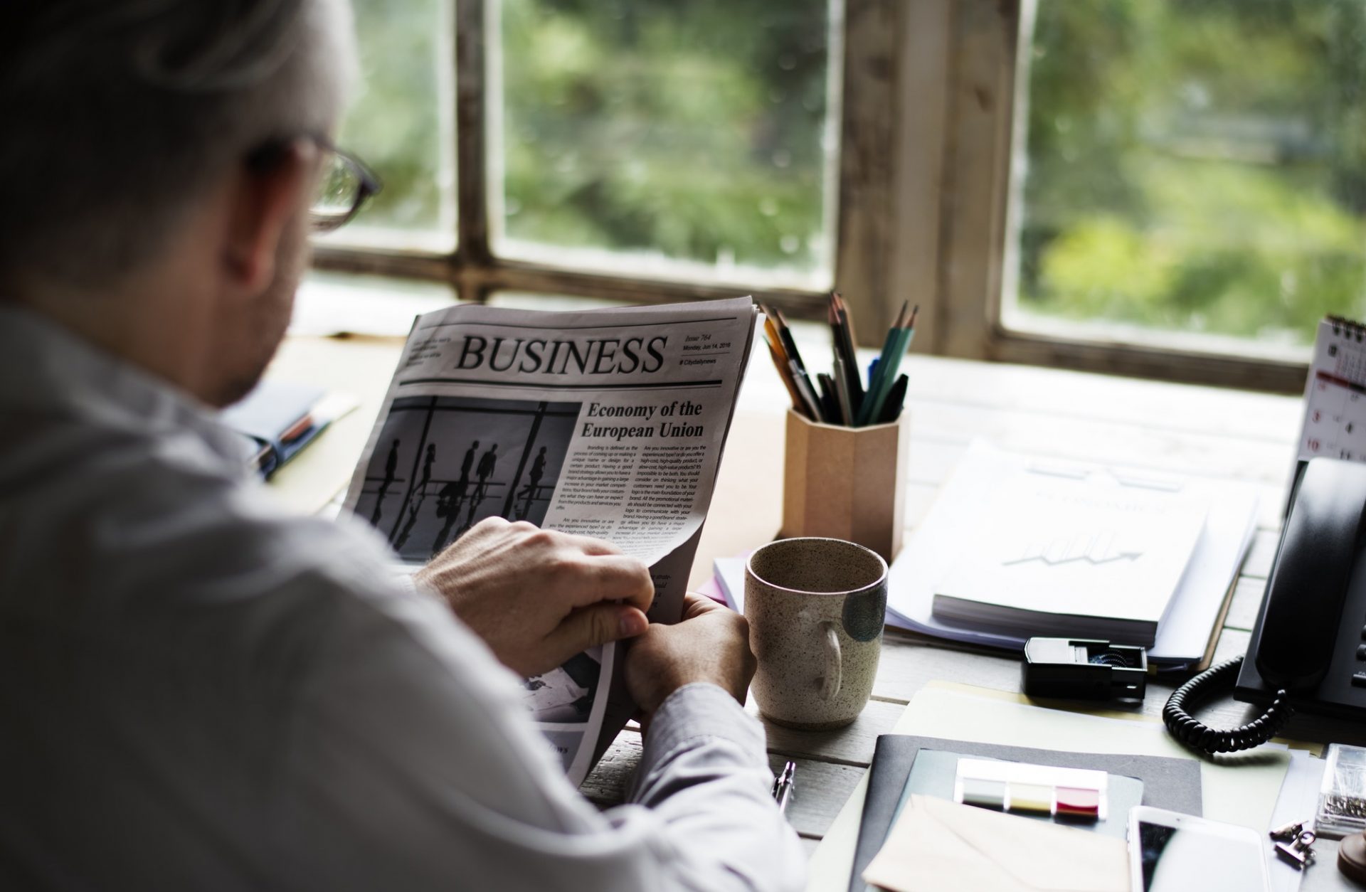 Businesspeople Reading Newspaper at Office Updating News