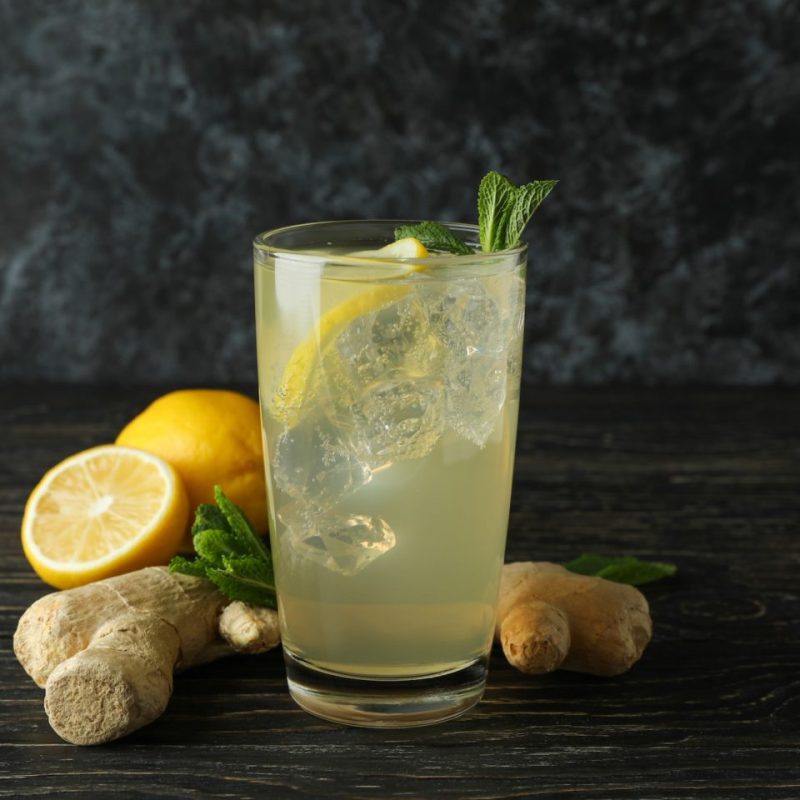 Glass of ginger - lemon drink and ingredients on wooden table