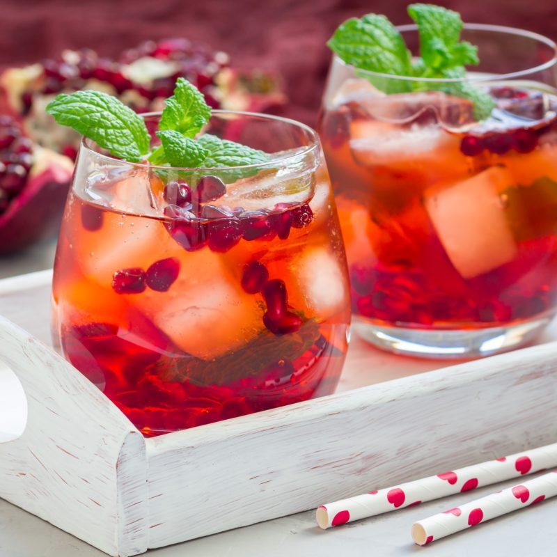 Mojito cocktail with pomegranate, mint, lemon juice and ice in glass, square