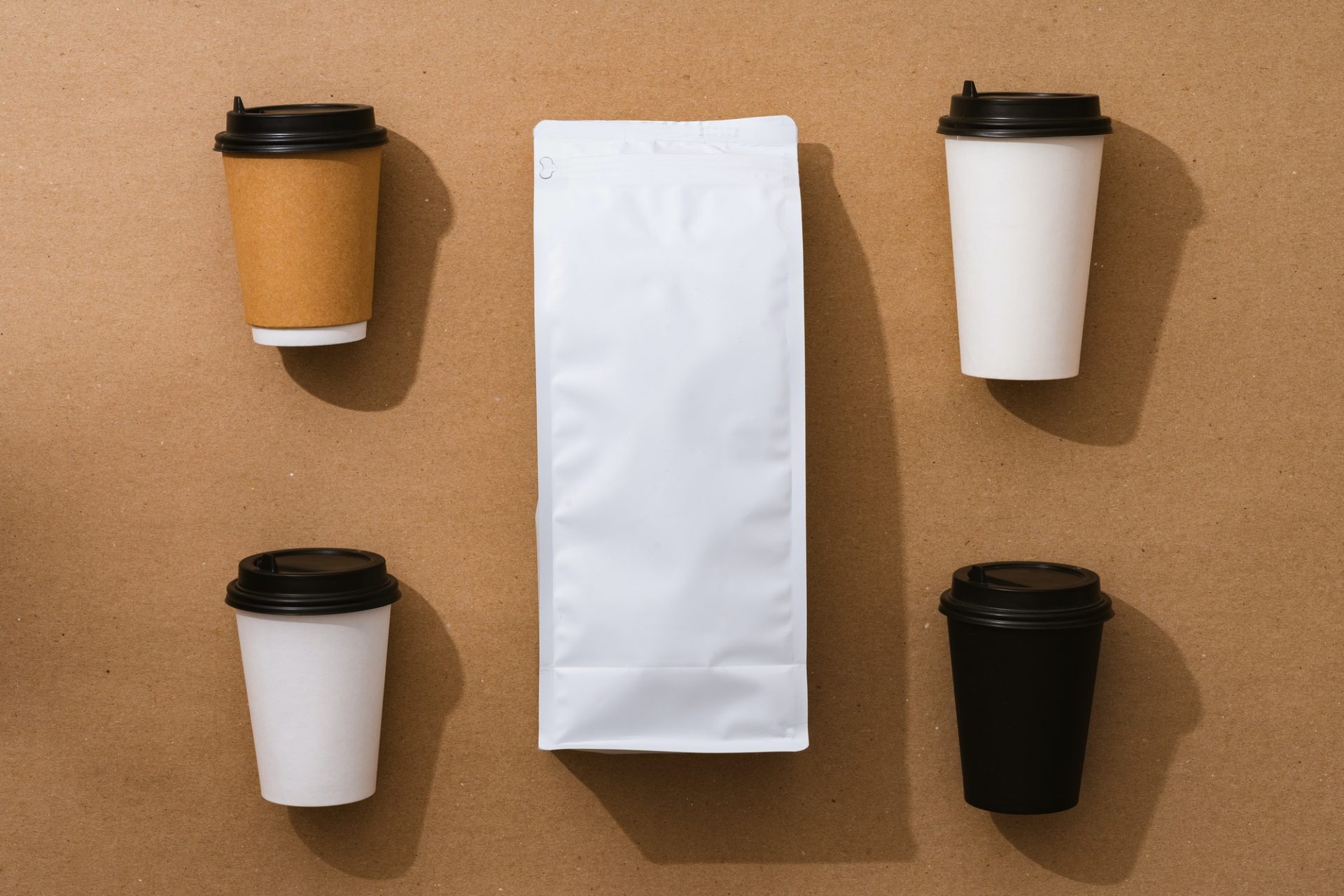 Blank coffee package with copy space and takeout cups on beige background