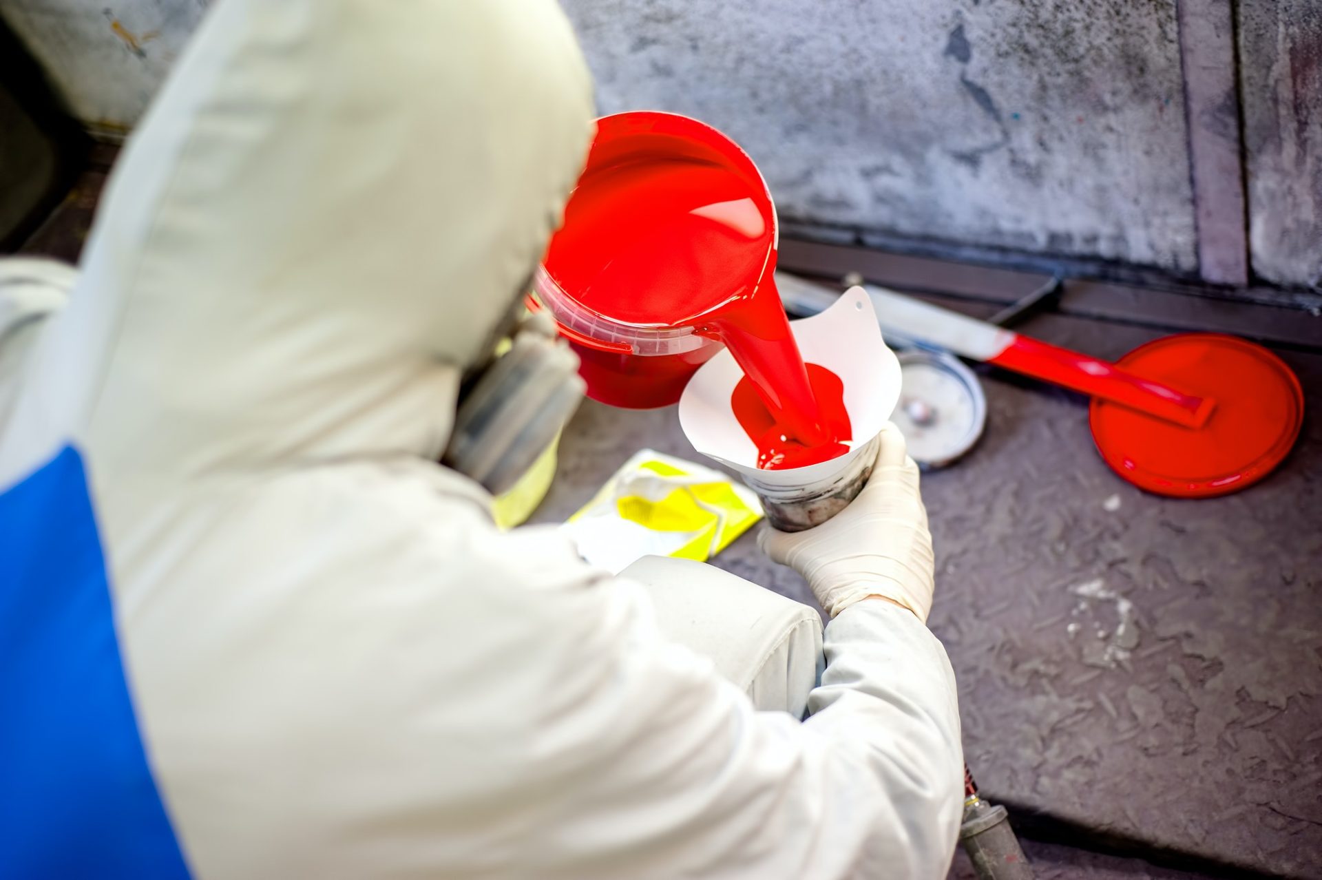 Auto mechanic mixing and pouring red paint for spraying and painting cars