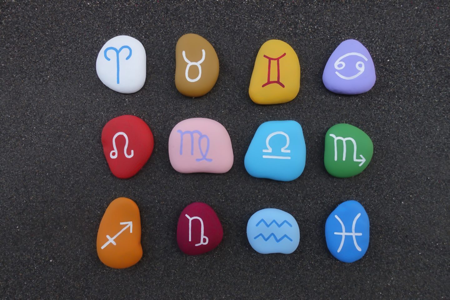 Astrological chinese signs painted and graved on stones over black volcanic sand