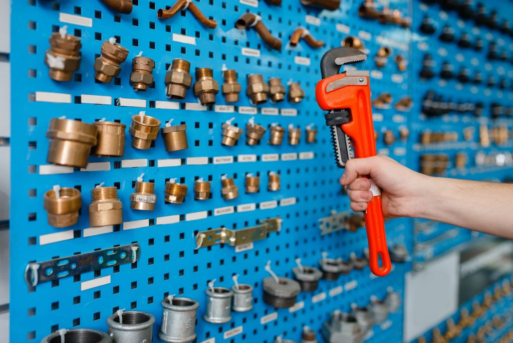 Plumber holds pipe wrench in plumbering store