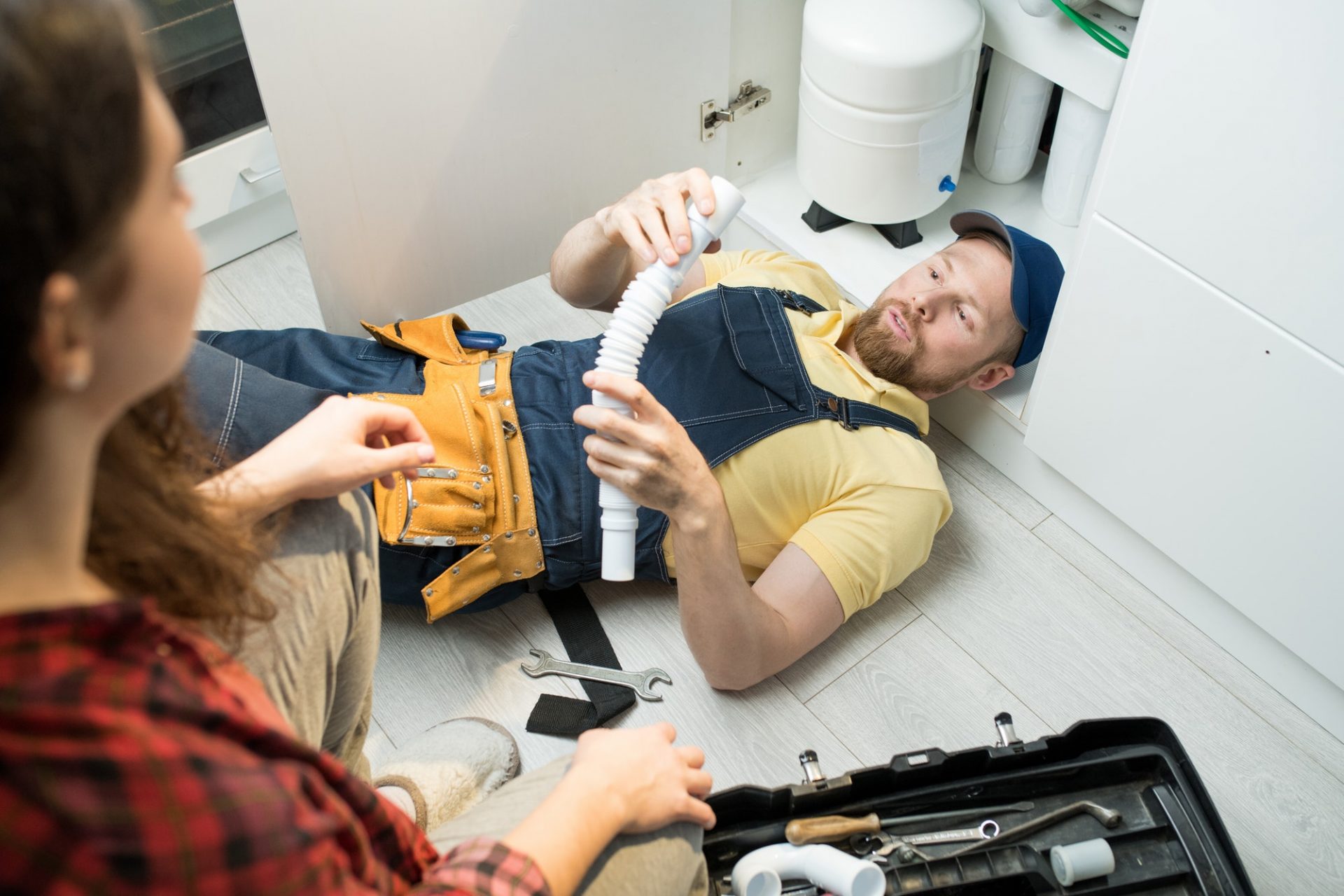 Young plumber changing trap under sink