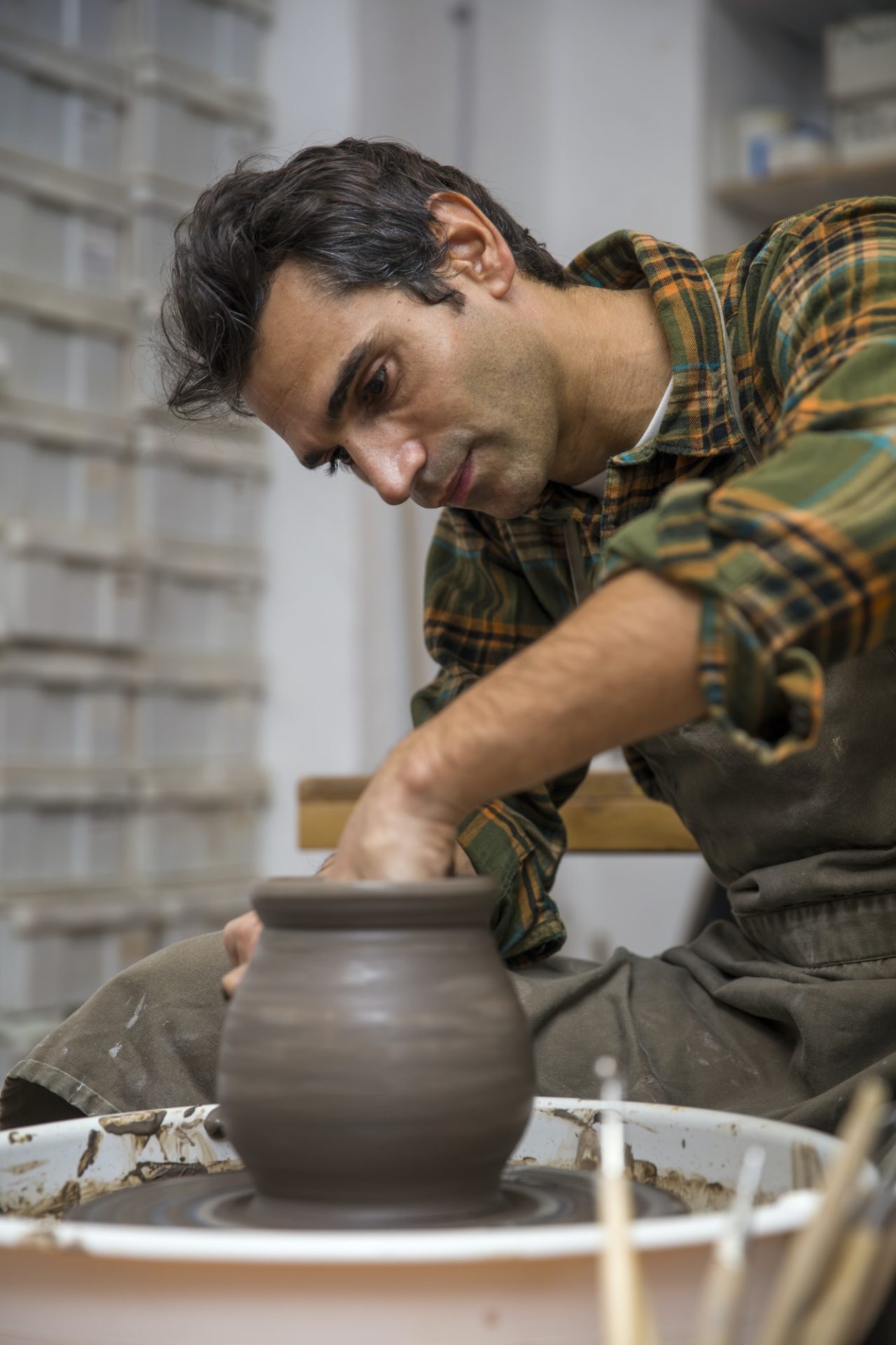 Artist makes clay pottery on a spin wheel in workshop