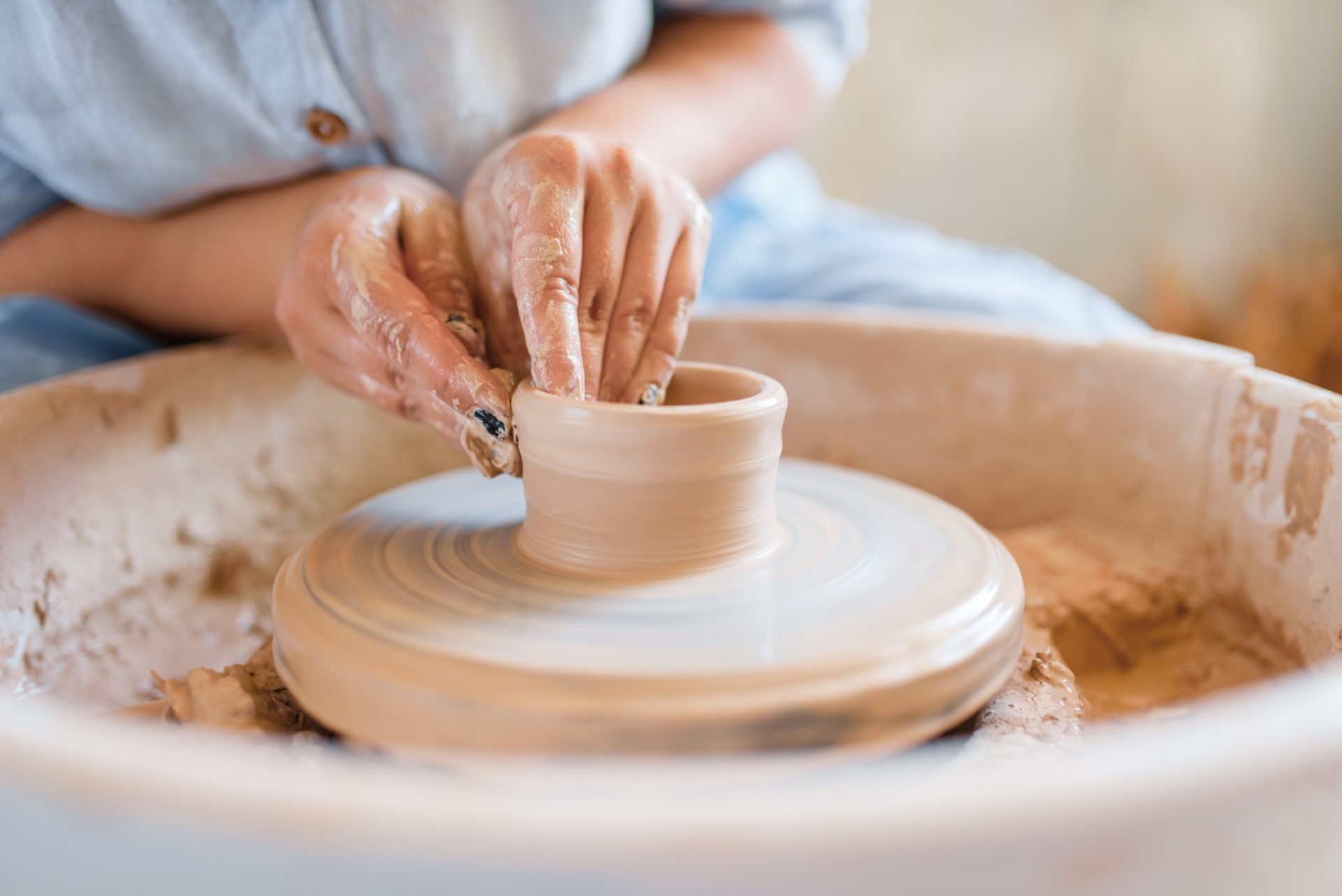Female potter making a pot on pottery wheel