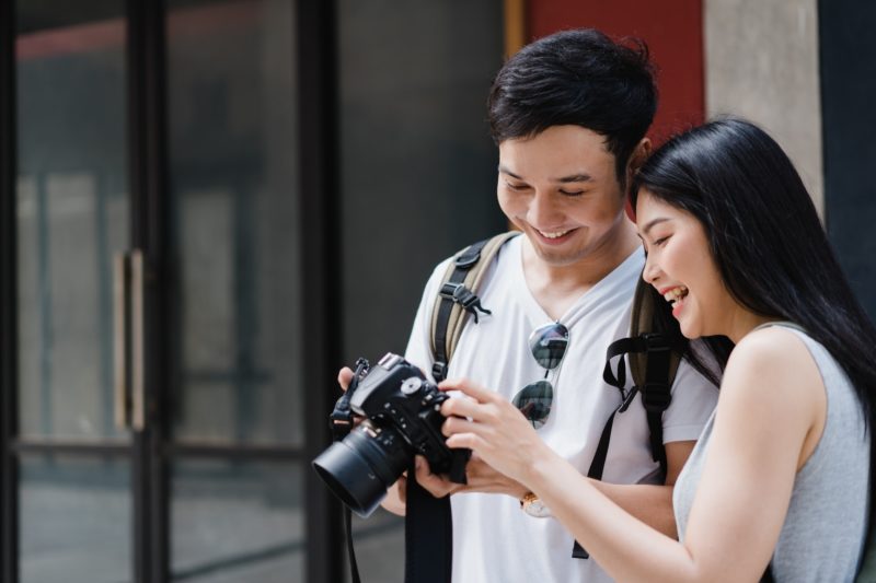 Asian couple using camera for take a picture while spending holiday.
