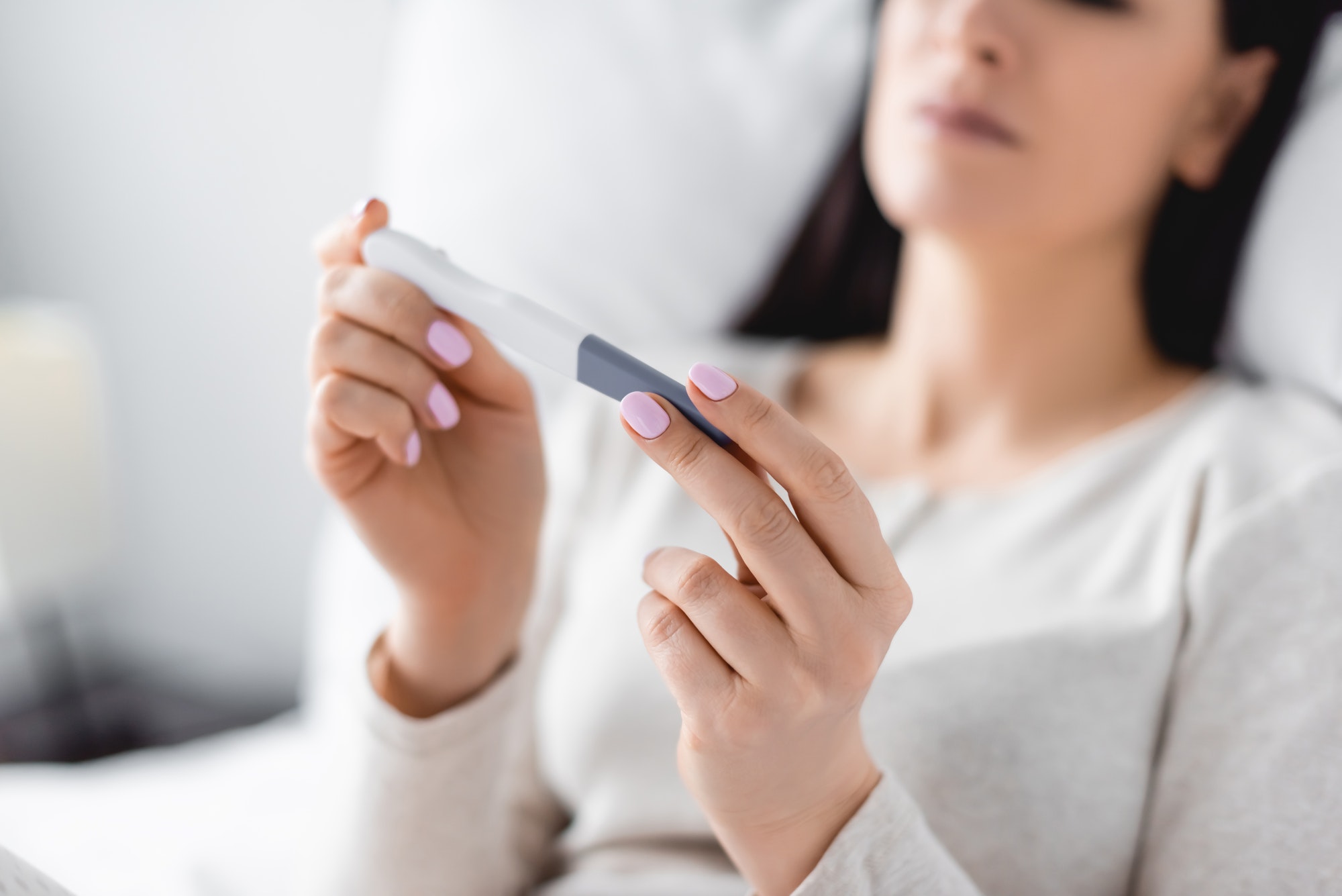 cropped view of depressed woman holding pregnancy test