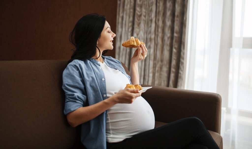 Pregnant woman with belly eating sweets