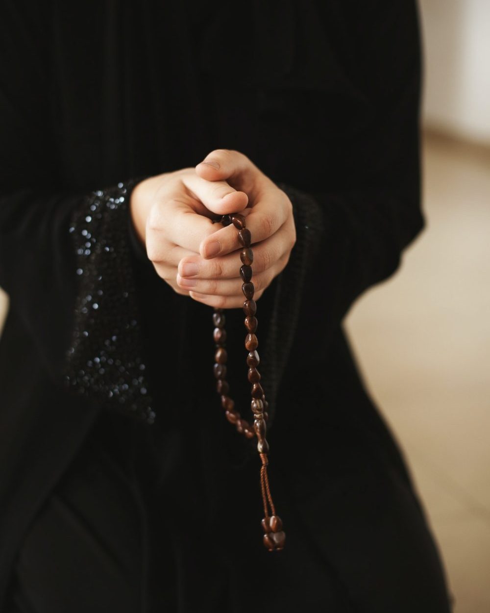 Prayer hands of a woman holding a rosary