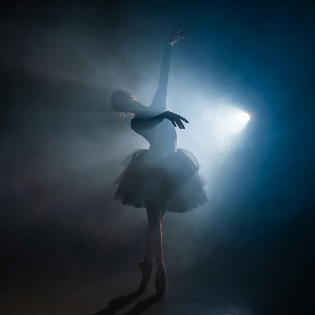 Young beautiful ballerina on smoke stage dancing modern ballet
