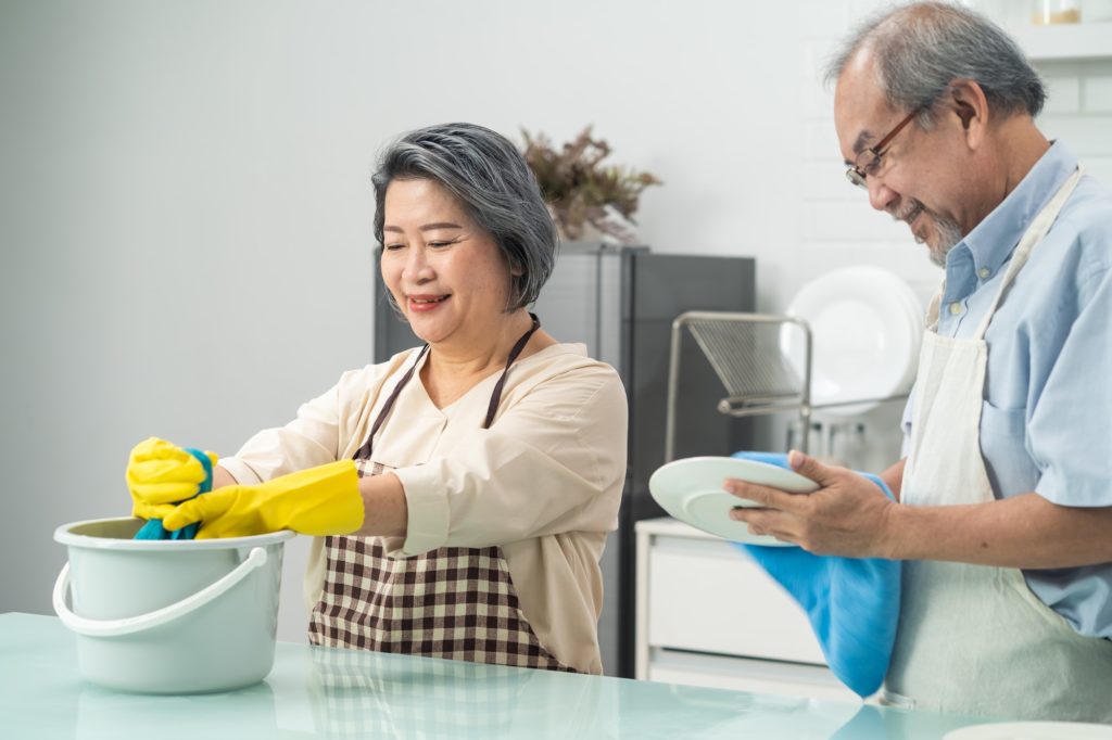 Asian young aged housewife twisting wet rag to clean the kitchen counter.