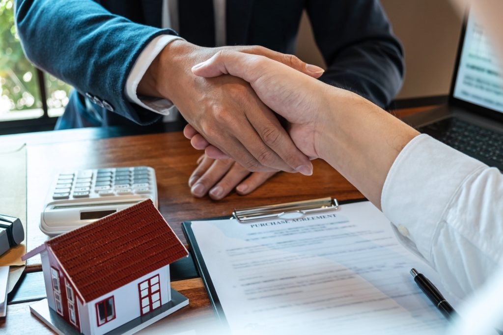Real estate agent are shaking hands after good deal and giving house