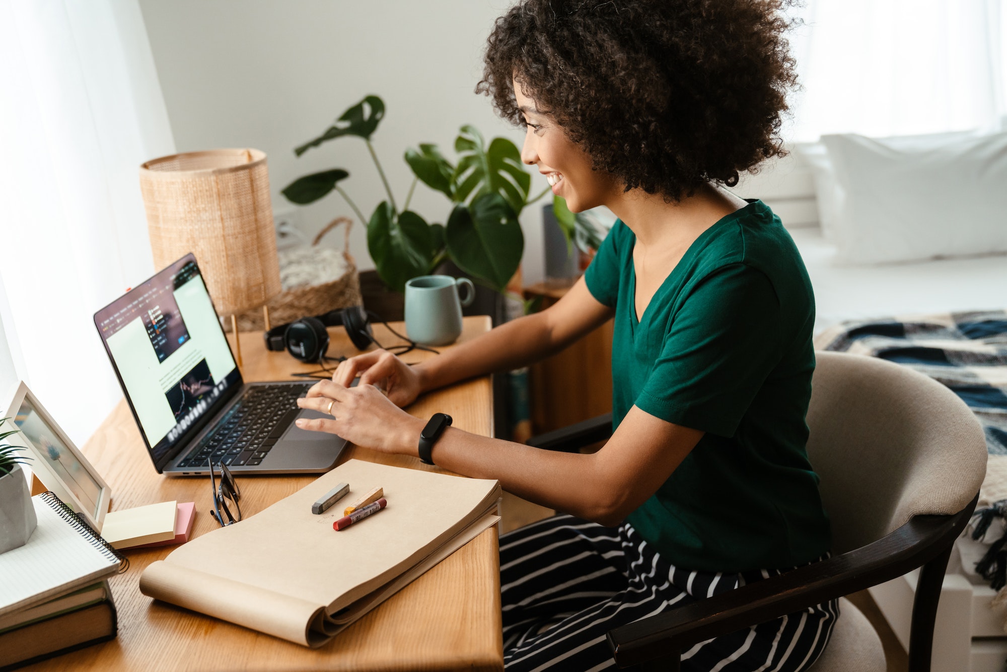 African american young woman sitting at desk and using laptop at home