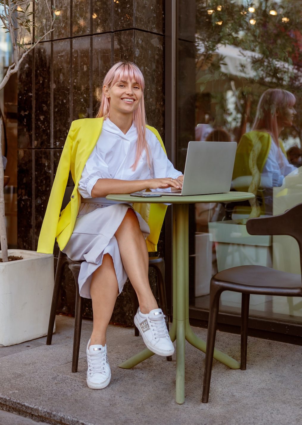 Joyful woman using modern notebook at outdoor cafe