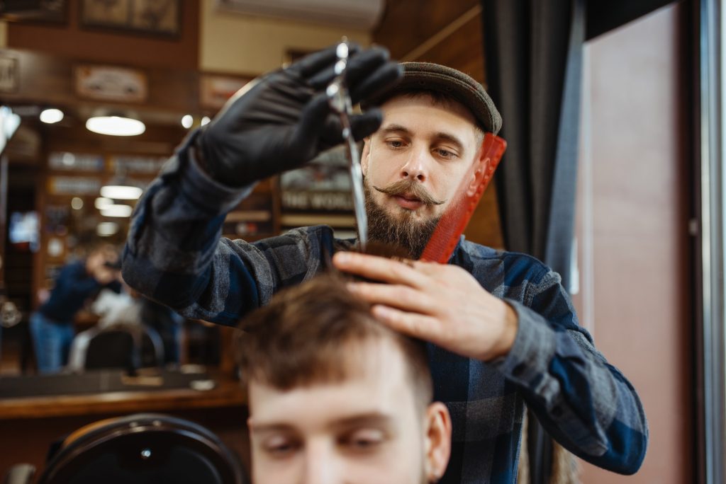Barber makes stylish haircut to client, barbershop