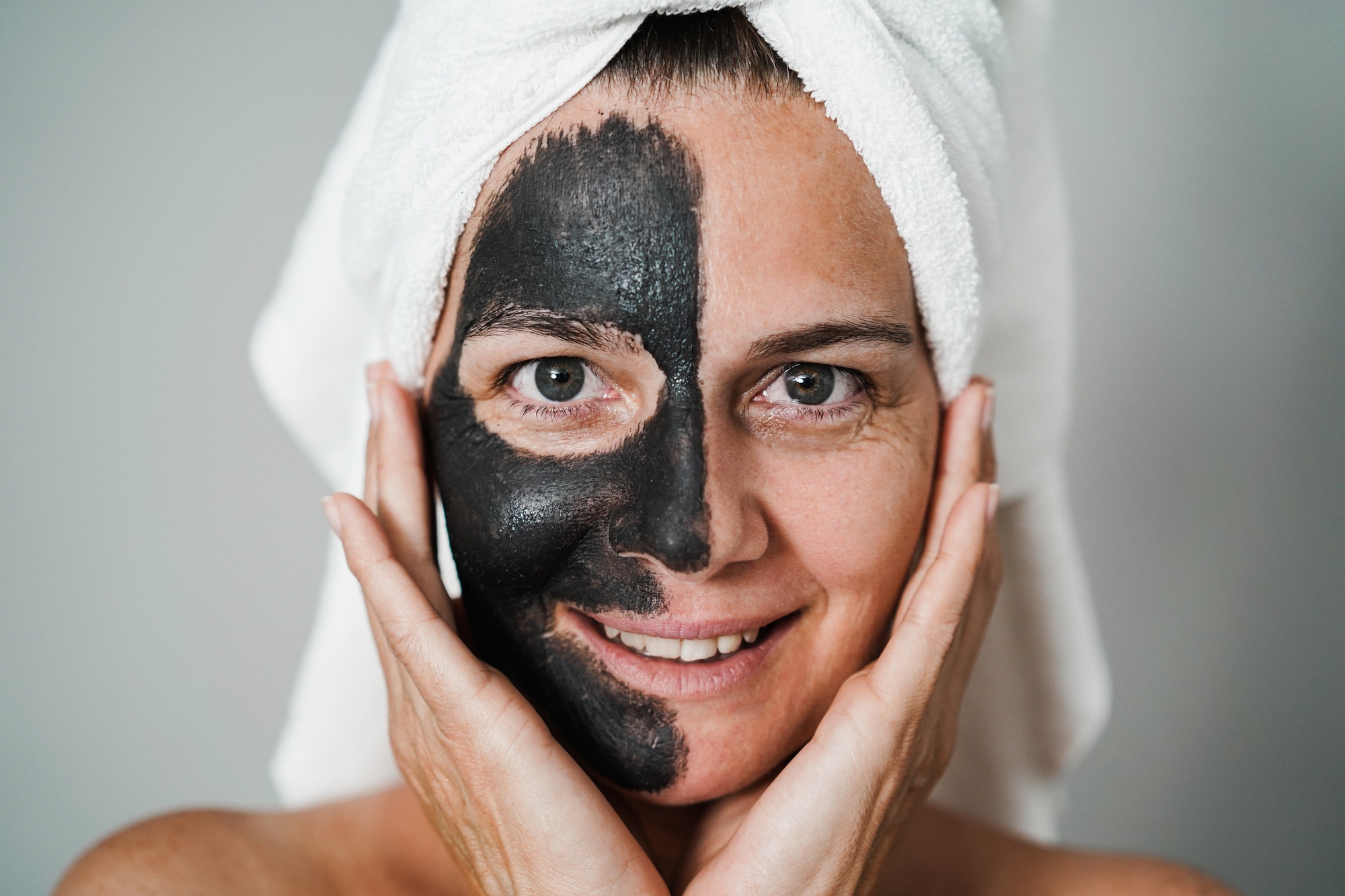 Caucasian woman using natural charcoal black mask for skin care theraphy