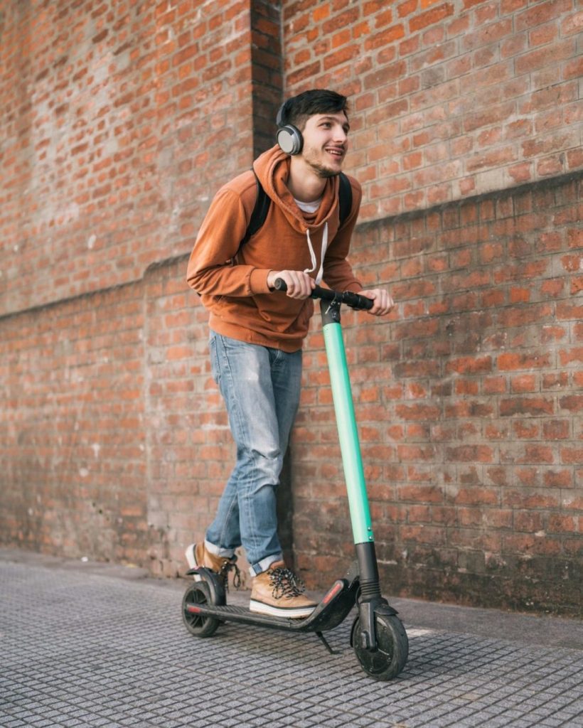 Young man driving electric scooter.
