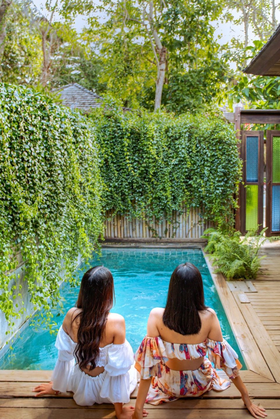 Young attractive couple relaxing by a swimming pool in a tropical garden