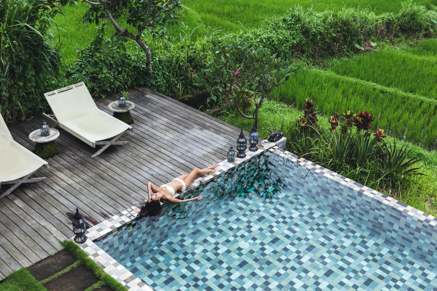 Young slim girl relaxing near luxury pool in Bali rice fields