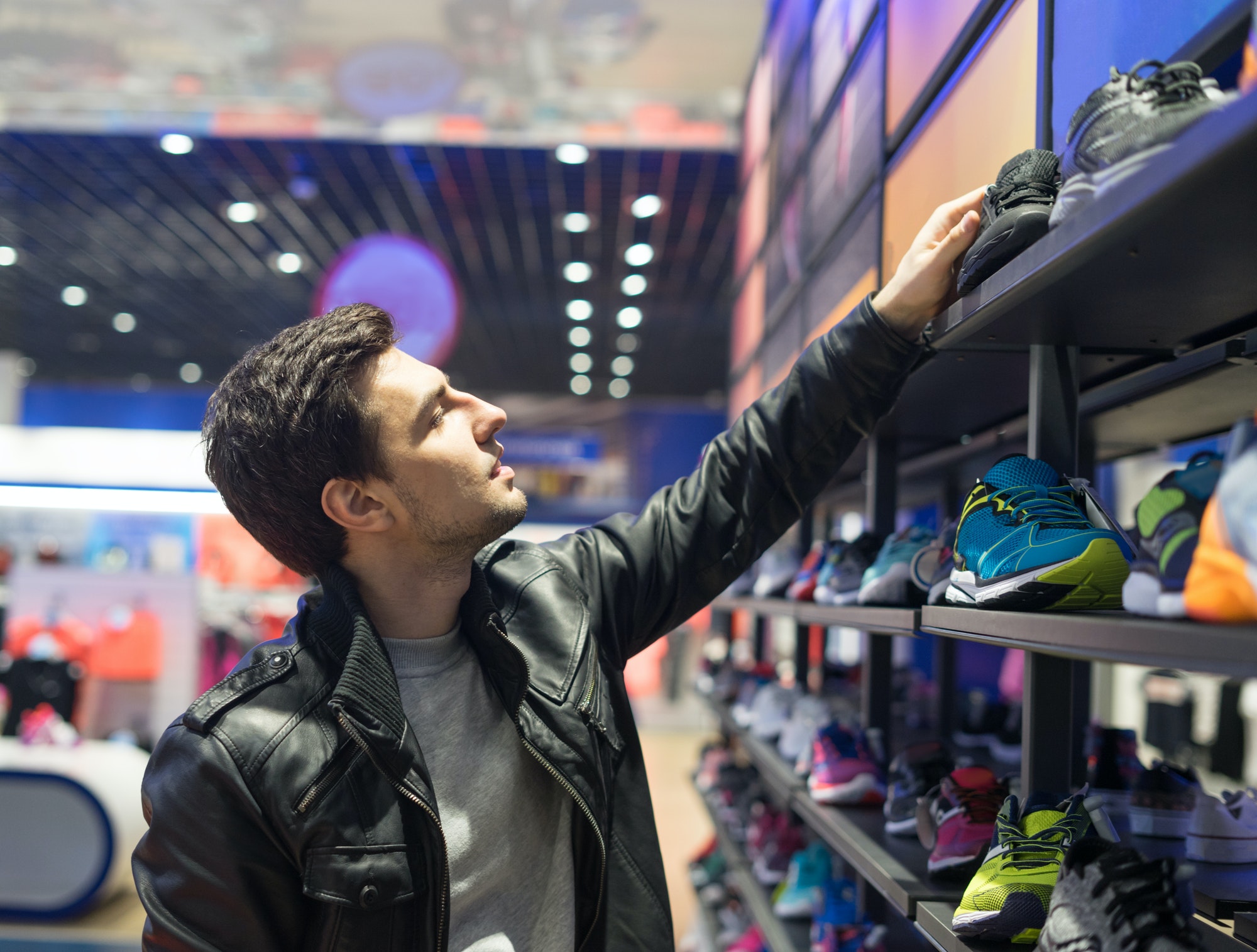 young male customer choosing sneakers