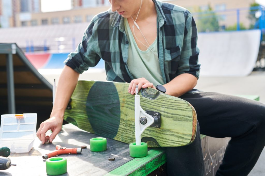 Young Man Fixing Skateboard