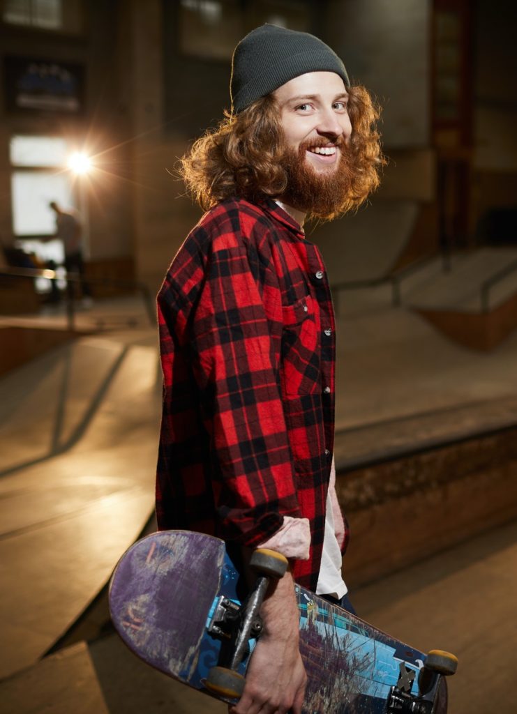 Smiling Young Man Holding Skateboard