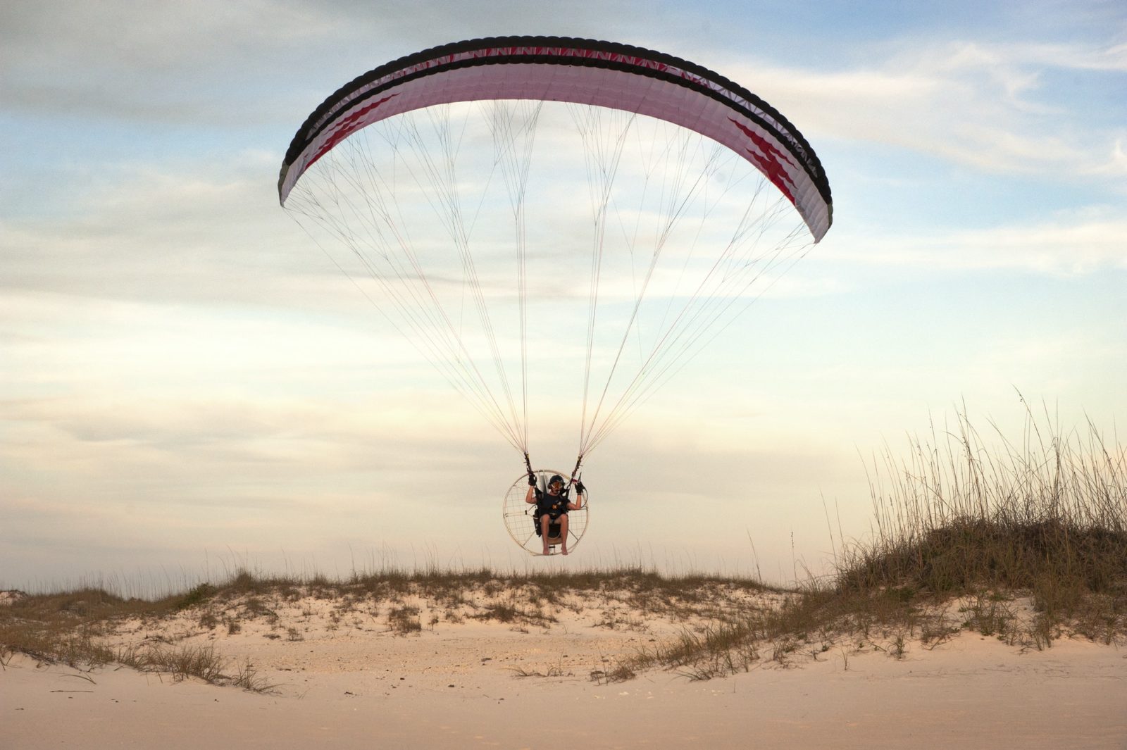 Man Paragliding Over Beach Against Sky
