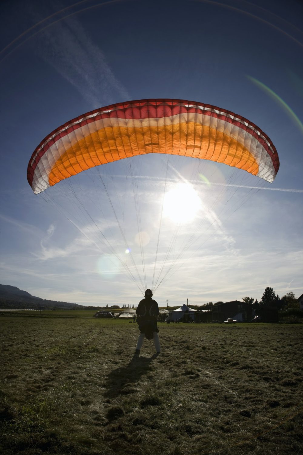 Mature male paraglider landing with parachute, Mount Saleve, Geneva, Switzerland
