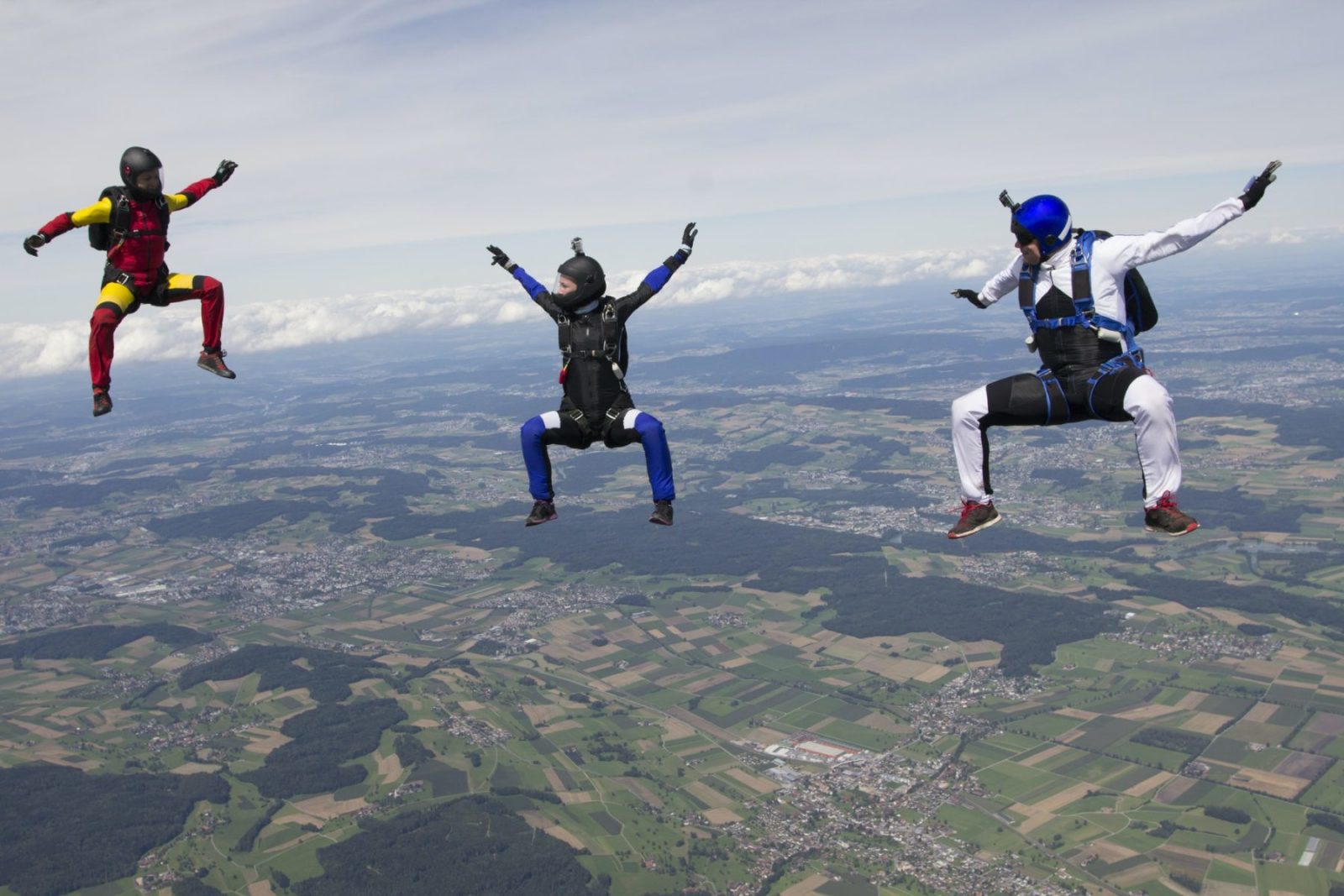Team of three skydivers in sit fly position over Buttwil, Luzern, Switzerland