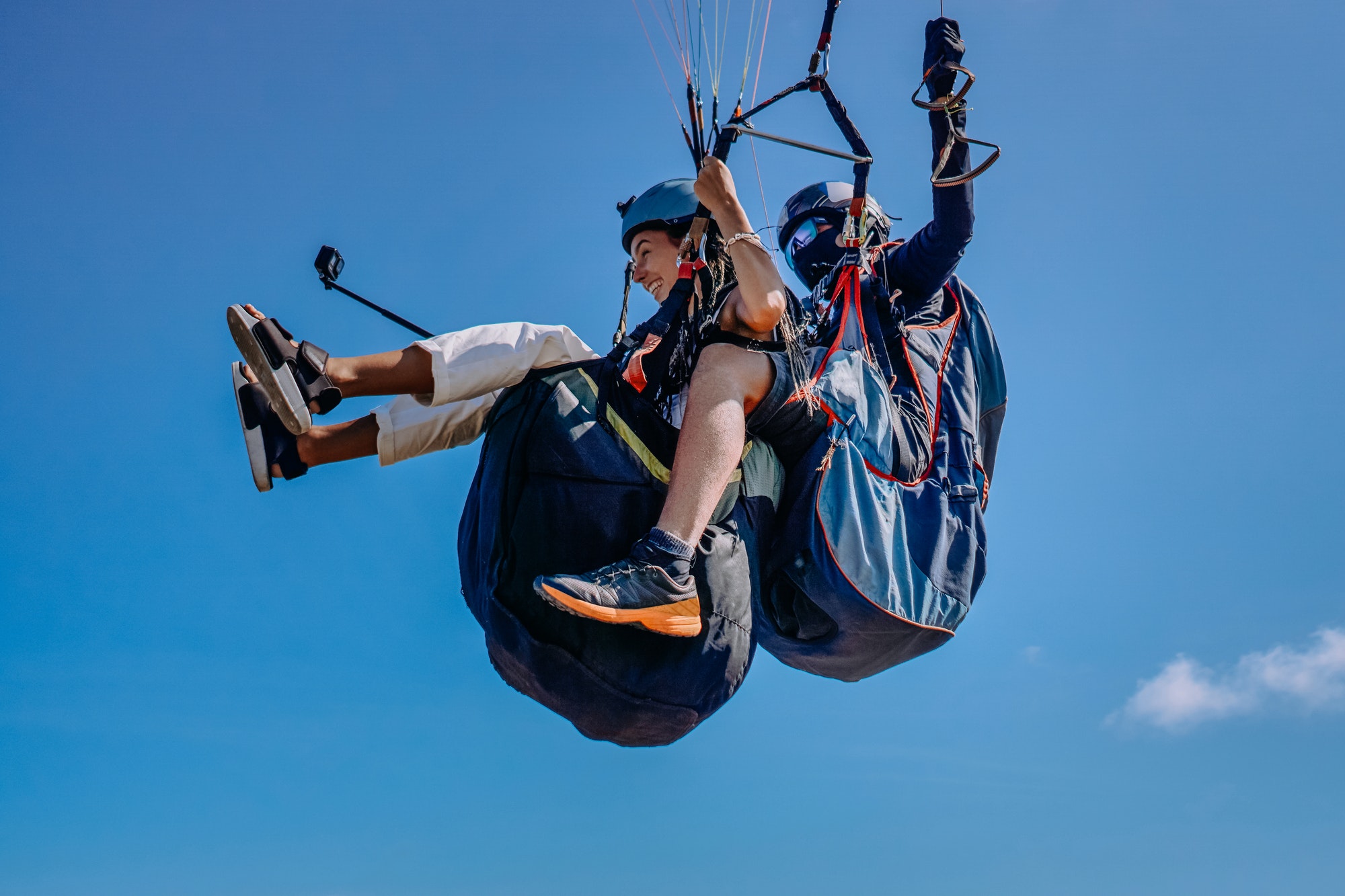 Woman with instructor flying on parachute against sky