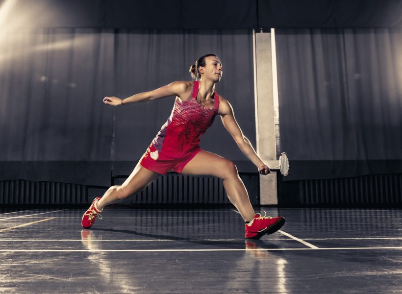 Young woman playing badminton at gym