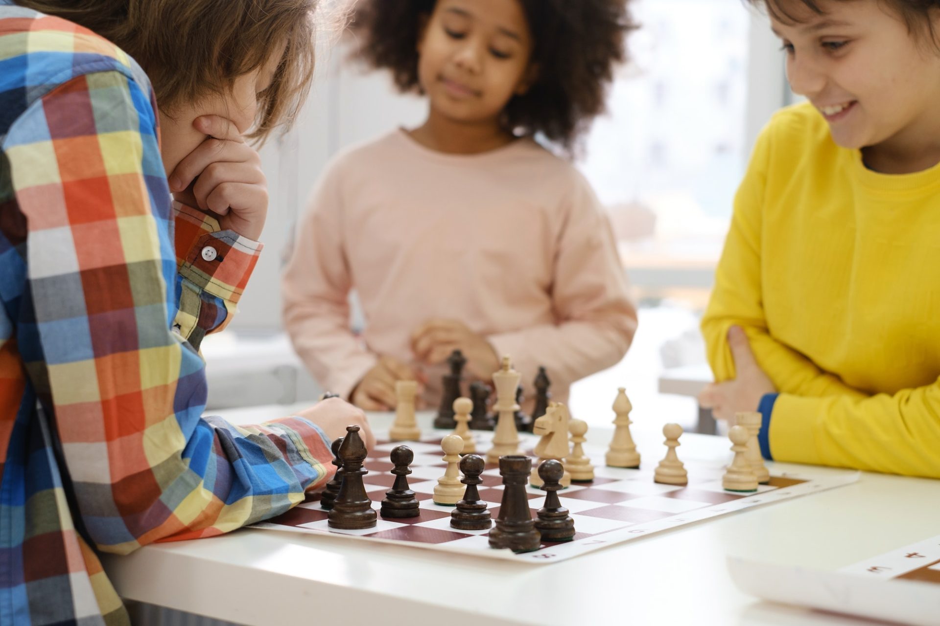 multiethnic kids playing chess board game at school